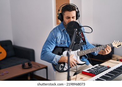 Young hispanic man singing song playing electric guitar at music studio - Powered by Shutterstock