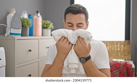 Young hispanic man smelling clothes at laundry room - Shutterstock ID 2304159771