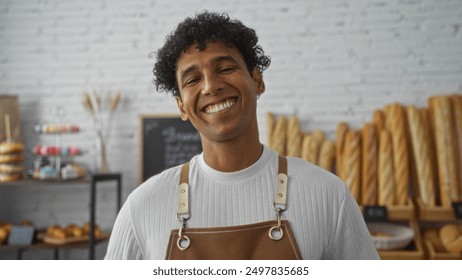 Young hispanic man smiling in a bakery shop interior with shelves of baguettes in the background - Powered by Shutterstock