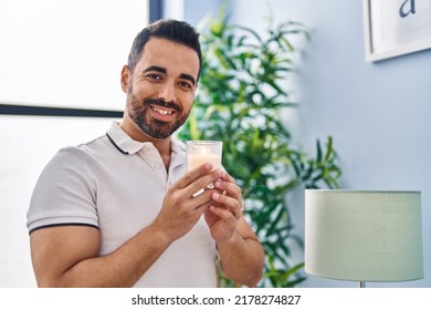 Young Hispanic Man Smiling Confident Smelling Candle At Home