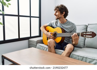 Young Hispanic Man Smiling Confident Playing Classical Guitar At Home