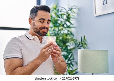 Young Hispanic Man Smiling Confident Smelling Candle At Home