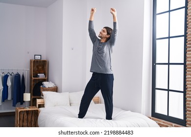 Young hispanic man smiling confident dancing on bed at bedroom
