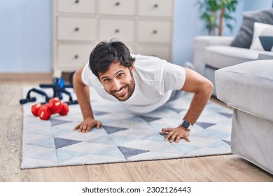 Young hispanic man smiling confident training push up at home