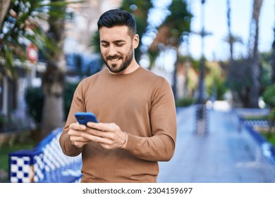 Young hispanic man smiling confident using smartphone at park - Powered by Shutterstock