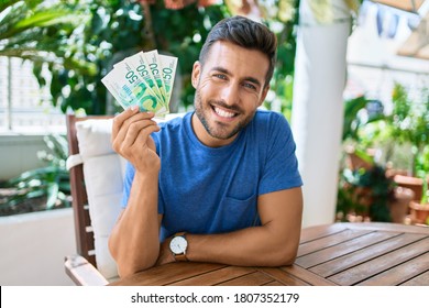 Young Hispanic Man Smiling Happy Holding Israeli Shekels Banknotes At The Terrace.