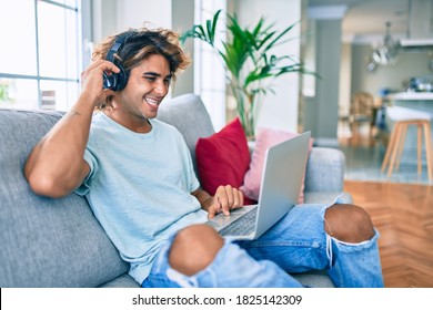 Young Hispanic Man Smiling Happy Using Laptop And Headphones At Home