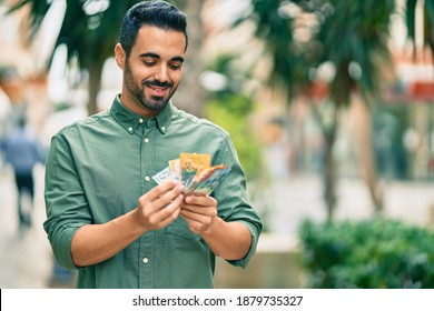 Young hispanic man smiling happy counting australian dollars at the city.