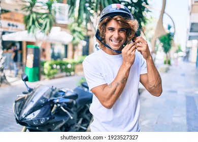 Young hispanic man smiling happy wearing moto helmet over motorcycle at the city - Powered by Shutterstock