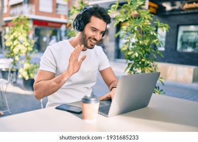 Young Hispanic Man Smiling Happy Doing Video Call Using Laptop And Headphones At Coffee Shop Terrace.