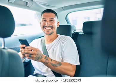 Young Hispanic Man Smiling Happy Using Smartphone Sitting On The Car.