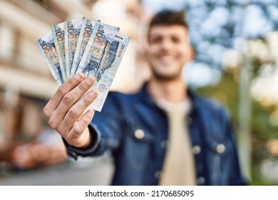 Young hispanic man smiling happy holding peruvian sol banknotes at the city - Shutterstock ID 2170685095