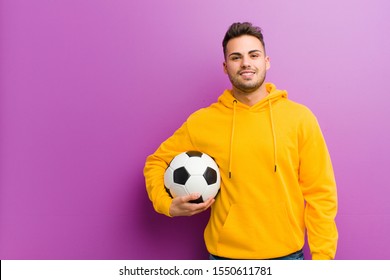 young hispanic man and soccer ball against purple background