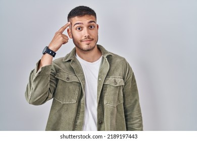 Young hispanic man standing over isolated background smiling pointing to head with one finger, great idea or thought, good memory  - Shutterstock ID 2189197443