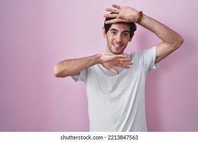 Young Hispanic Man Standing Over Pink Background Smiling Cheerful Playing Peek A Boo With Hands Showing Face. Surprised And Exited 