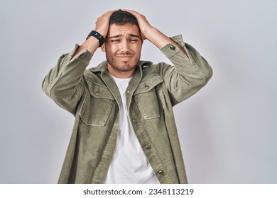 Young hispanic man standing over isolated background suffering from headache desperate and stressed because pain and migraine. hands on head.  - Powered by Shutterstock