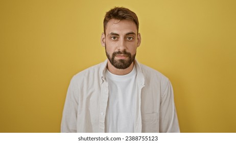 Young hispanic man standing with serious expression over isolated yellow background - Powered by Shutterstock