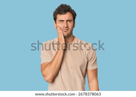 Young Hispanic man in studio having a strong teeth pain, molar ache.