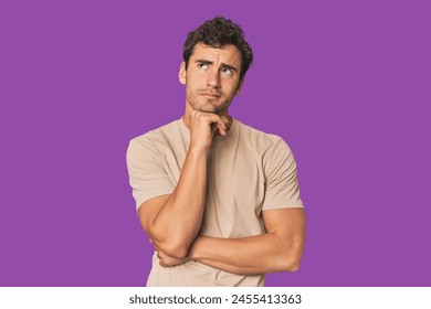 Young Hispanic man in studio thinking and looking up, being reflective, contemplating, having a fantasy. - Powered by Shutterstock