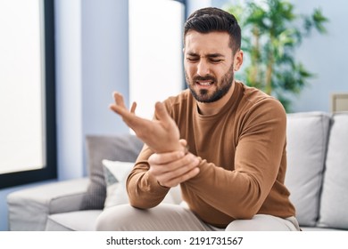 Young hispanic man suffering for wrist injury sitting on sofa at home - Shutterstock ID 2191731567