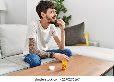 Young Hispanic Man Taking Pills Sitting On The Sofa At Home