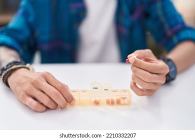 Young Hispanic Man Taking Pills Treatment Sitting On Table At Home