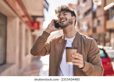 Young hispanic man talking on the smartphone drinking coffee at street - Powered by Shutterstock