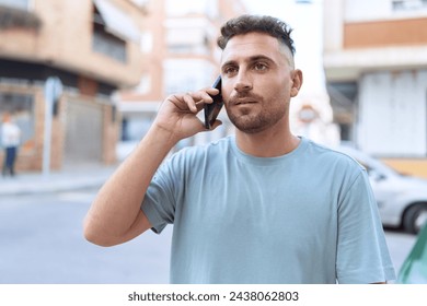 Young hispanic man talking on smartphone with serious expression at street - Powered by Shutterstock