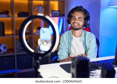 Young hispanic man and tattoos recording tutorial and smartphone happy face smiling and crossed arms looking at the camera  positive person  