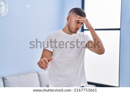 Young hispanic man touching head for dizzy standing at home