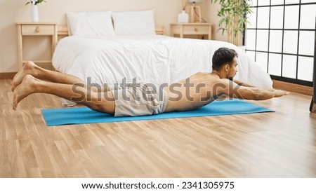 Young hispanic man training column exercise at bedroom