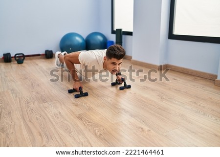 Young hispanic man training push up at sport center