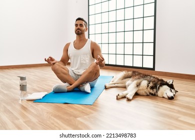 Young Hispanic Man Training Yoga With Dog At Sport Center