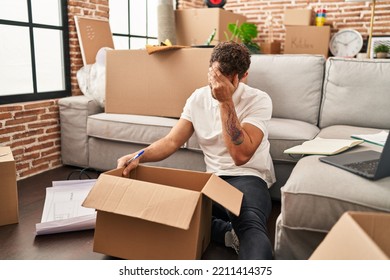 Young Hispanic Man Unboxing Package With Worry Expression At New Home