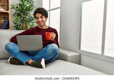 Young Hispanic Man Using Laptop Sitting On The Sofa At Home.