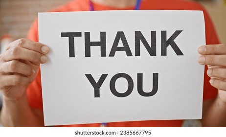 Young hispanic man volunteer holding thank you banner at charity center