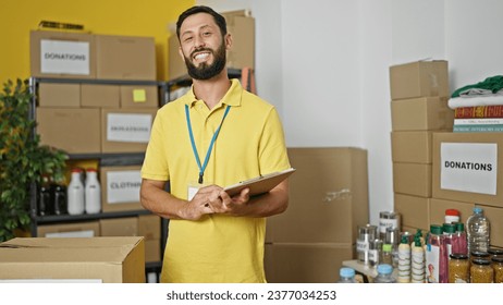 Young hispanic man volunteer smiling confident writing on document at charity center - Powered by Shutterstock