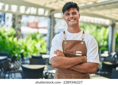 Young hispanic man waiter smiling confident standing with arms crossed gesture at coffee shop terrace - Powered by Shutterstock