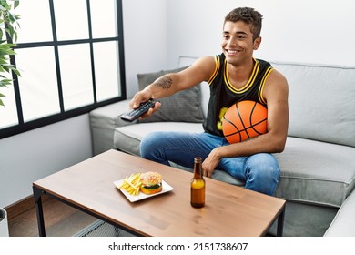 Young Hispanic Man Watching Basketball Game On Tv At Home