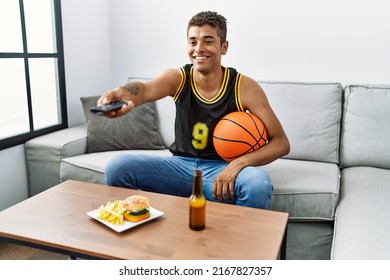 Young Hispanic Man Watching Basketball Game On Tv At Home