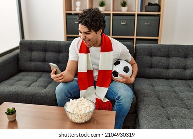 Young Hispanic Man Watching Soccer Match And Supporting Team At Home.