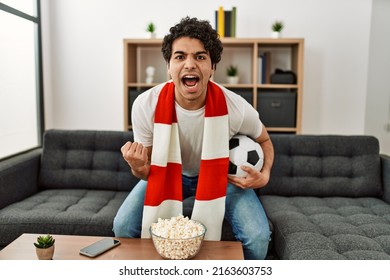 Young Hispanic Man Watching Soccer Match And Supporting Team At Home.