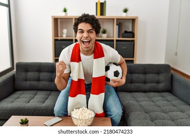 Young Hispanic Man Watching Soccer Match And Supporting Team At Home.