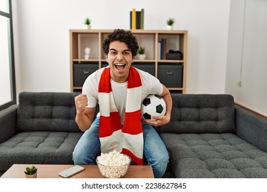 Young hispanic man watching soccer match and supporting team at home. - Powered by Shutterstock