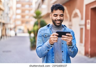 Young Hispanic Man Watching Video On Smartphone At Street