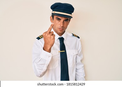 Young Hispanic Man Wearing Airplane Pilot Uniform Showing Middle Finger, Impolite And Rude Expression 