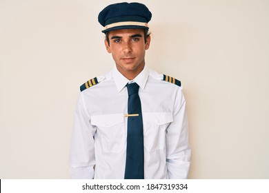 Young Hispanic Man Wearing Airplane Pilot Uniform Looking Sleepy And Tired, Exhausted For Fatigue And Hangover, Lazy Eyes In The Morning. 