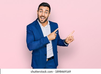 Young Hispanic Man Wearing Business Jacket Smiling And Looking At The Camera Pointing With Two Hands And Fingers To The Side. 