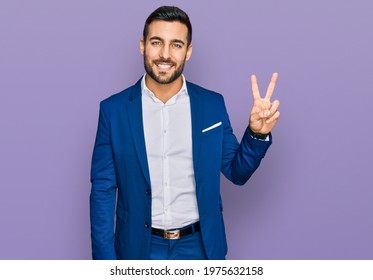 Young Hispanic Man Wearing Business Jacket Showing And Pointing Up With Fingers Number Two While Smiling Confident And Happy. 