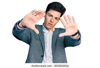 Young hispanic man wearing business clothes doing frame using hands palms and fingers, camera perspective 